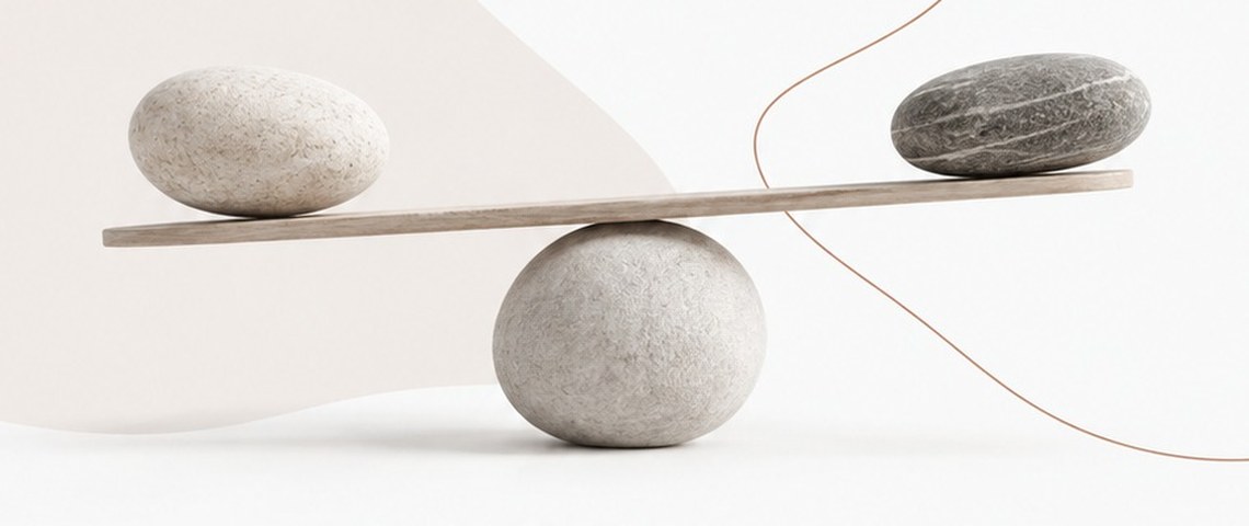 Three balanced stones on a wooden beam, representing the balance between opposing leadership qualities